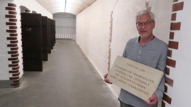 Gerald Hacke mit historischer Tafel im sanierten Zellengang der Gedenkstätte Münchner Platz Dresden