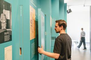 Ein Besucher steht in der Ausstellung und betrachtet eine Texttafel