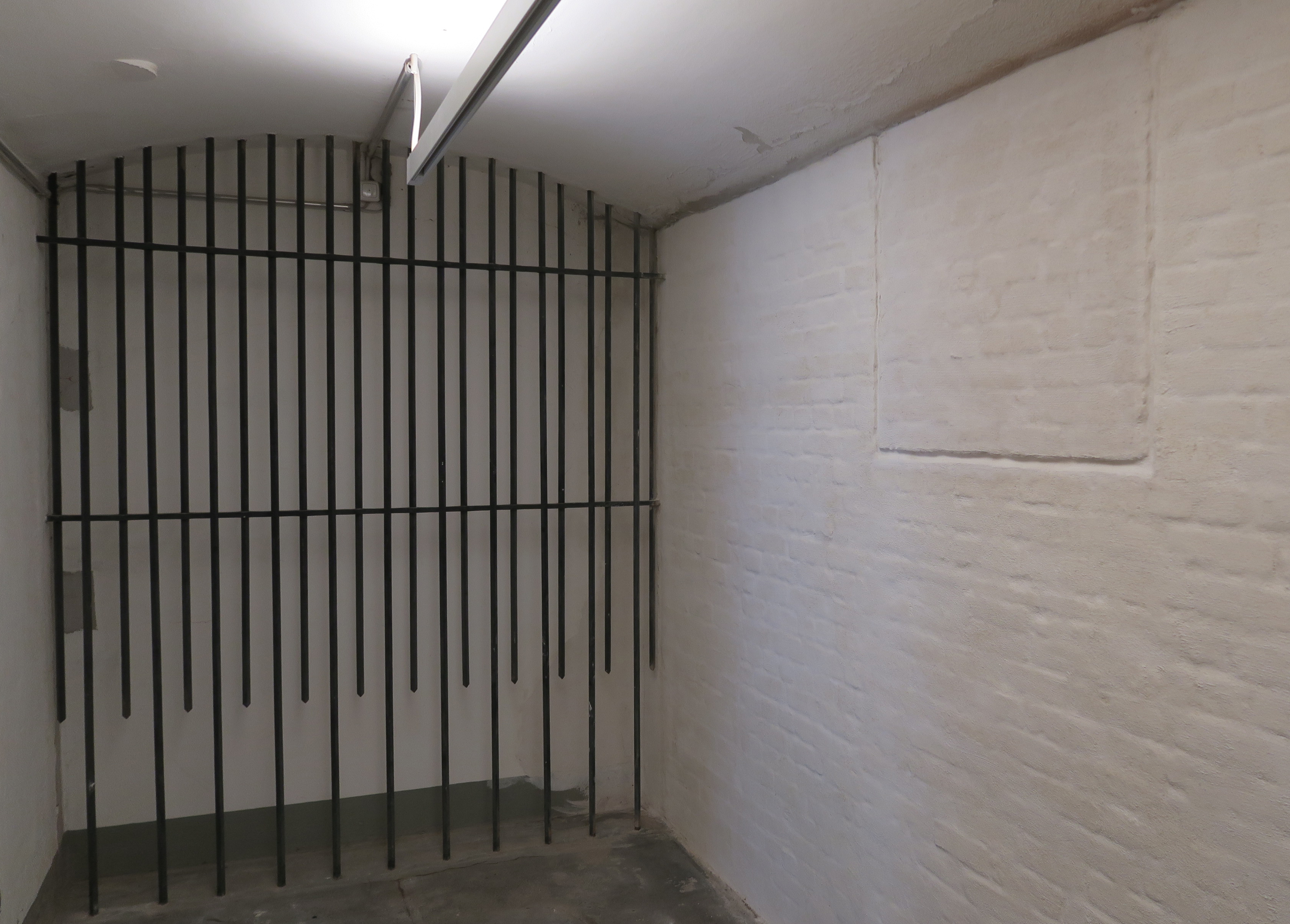 Rechts an der Wand des Zellengangs sind die Umrisse eines zugemauerten Fensters zu sehen, links eine Gitter-Installation des Künstlers Arndt Wittig von 1968